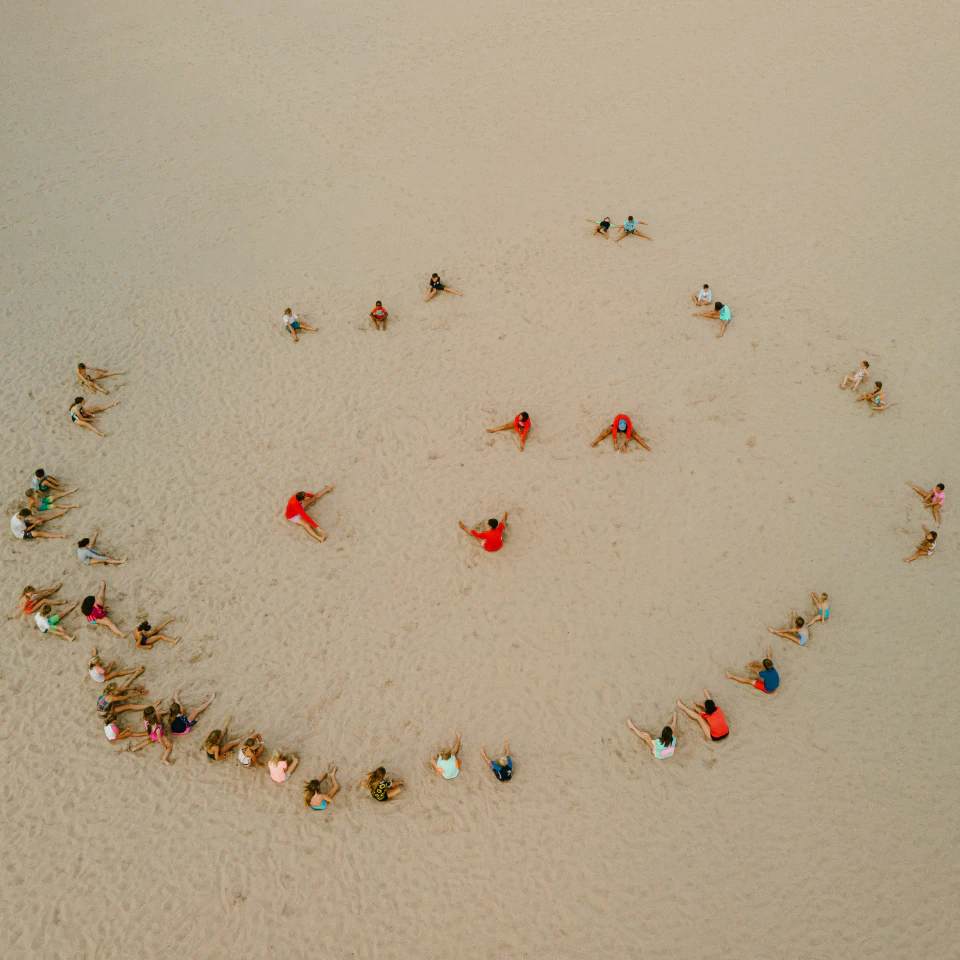 summer campers sitting in a circle at the beach